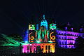 Das Schweriner Schloss bei Nacht wird von vielen bunten Farben angeleuchtet, die die Fassade betonen. Grüne Laserstrahlen kommen aus Richtung des Schlosses. 