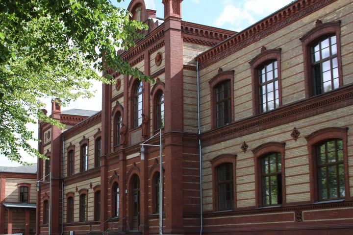 Eine nähere Aufnahme des Schulgebäudes zeigt den dreiachsigem Mittelrisalit und einen der einachsigen Seitenrisaliten aus roten und gelben Ziegeln.